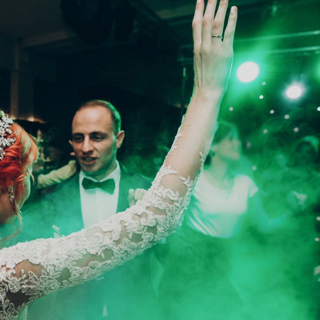 Newlywed couple dancing bathed in green dance floor lighting